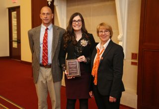 Kira Barclay with alumni award standing between Dean Schmittmann and Hal Schenck